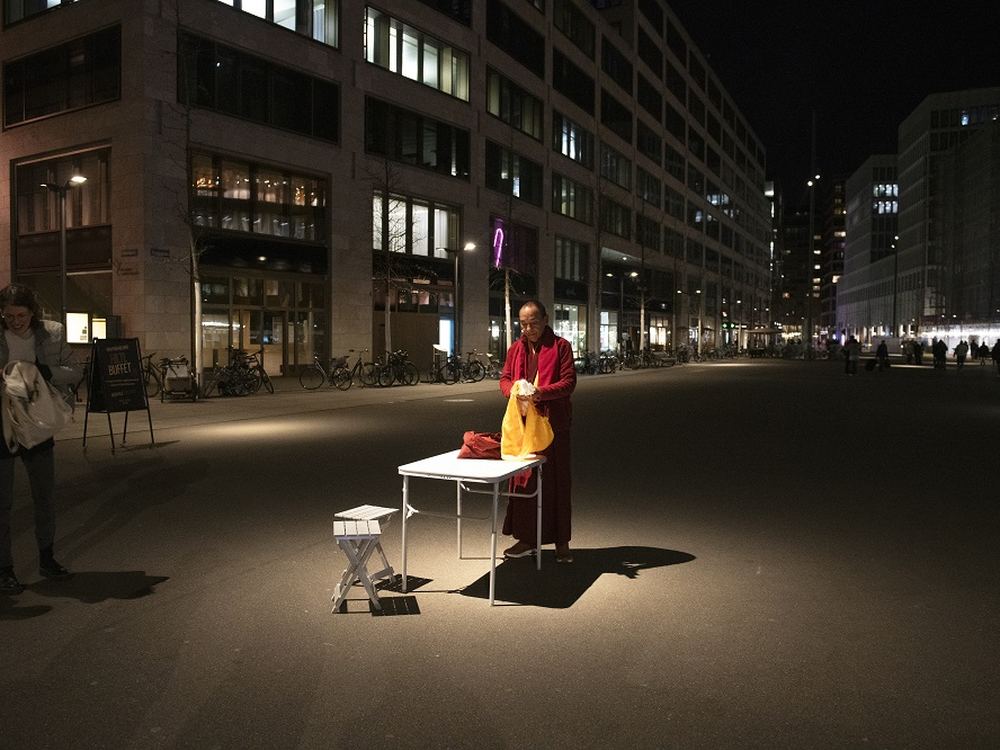 A lone runner at a table with a candle on a Zurich street at night