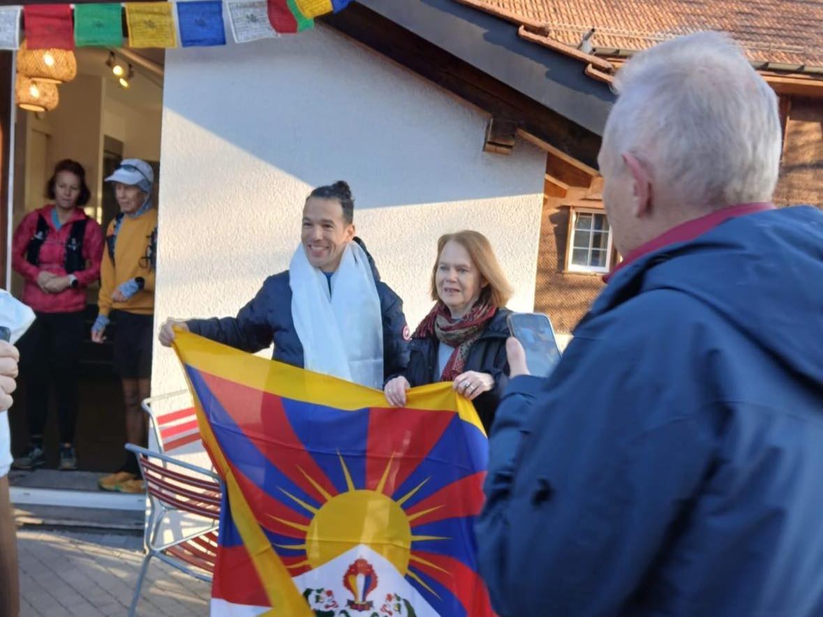 Dominik Erne with a Tibetan flag in front of a house with prayer flags in Trogen