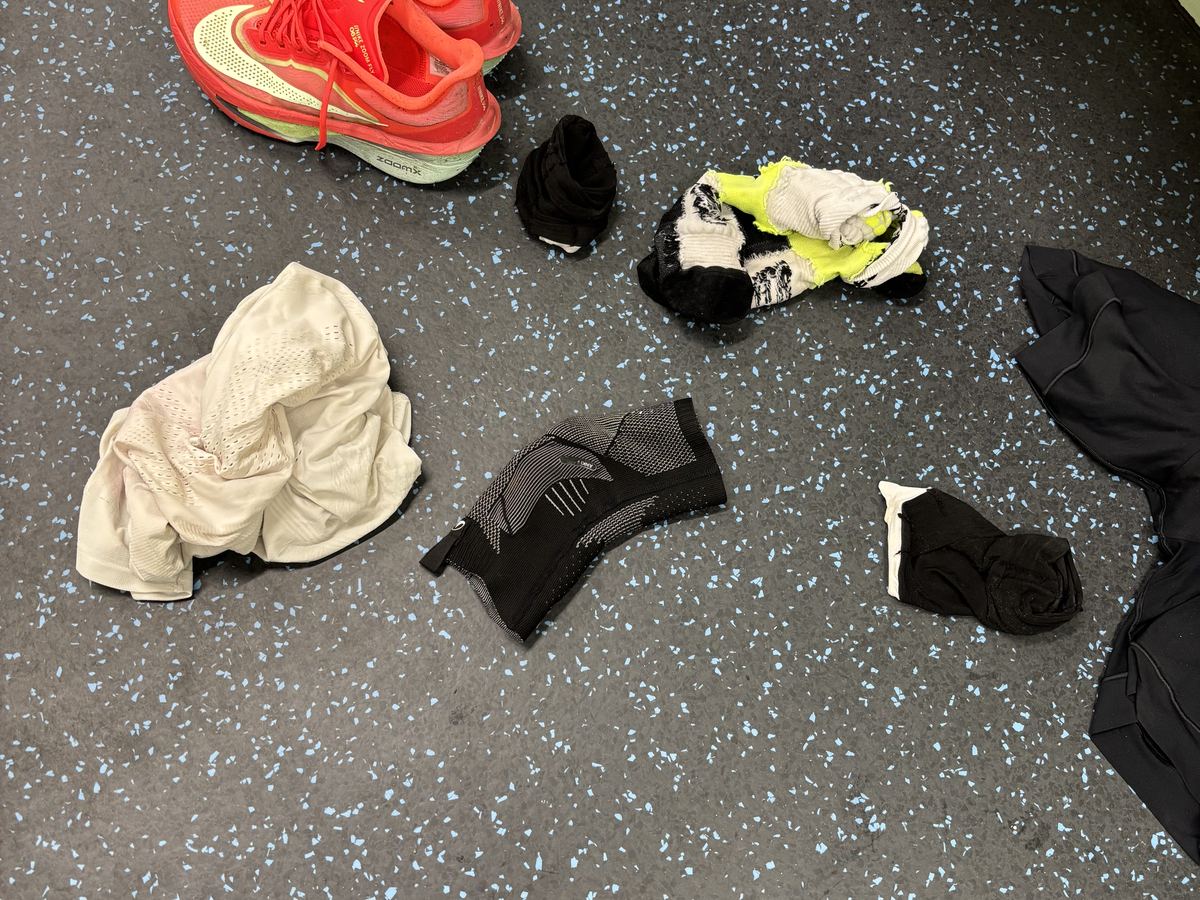 Wet running shoes and clothes laid out on a floor